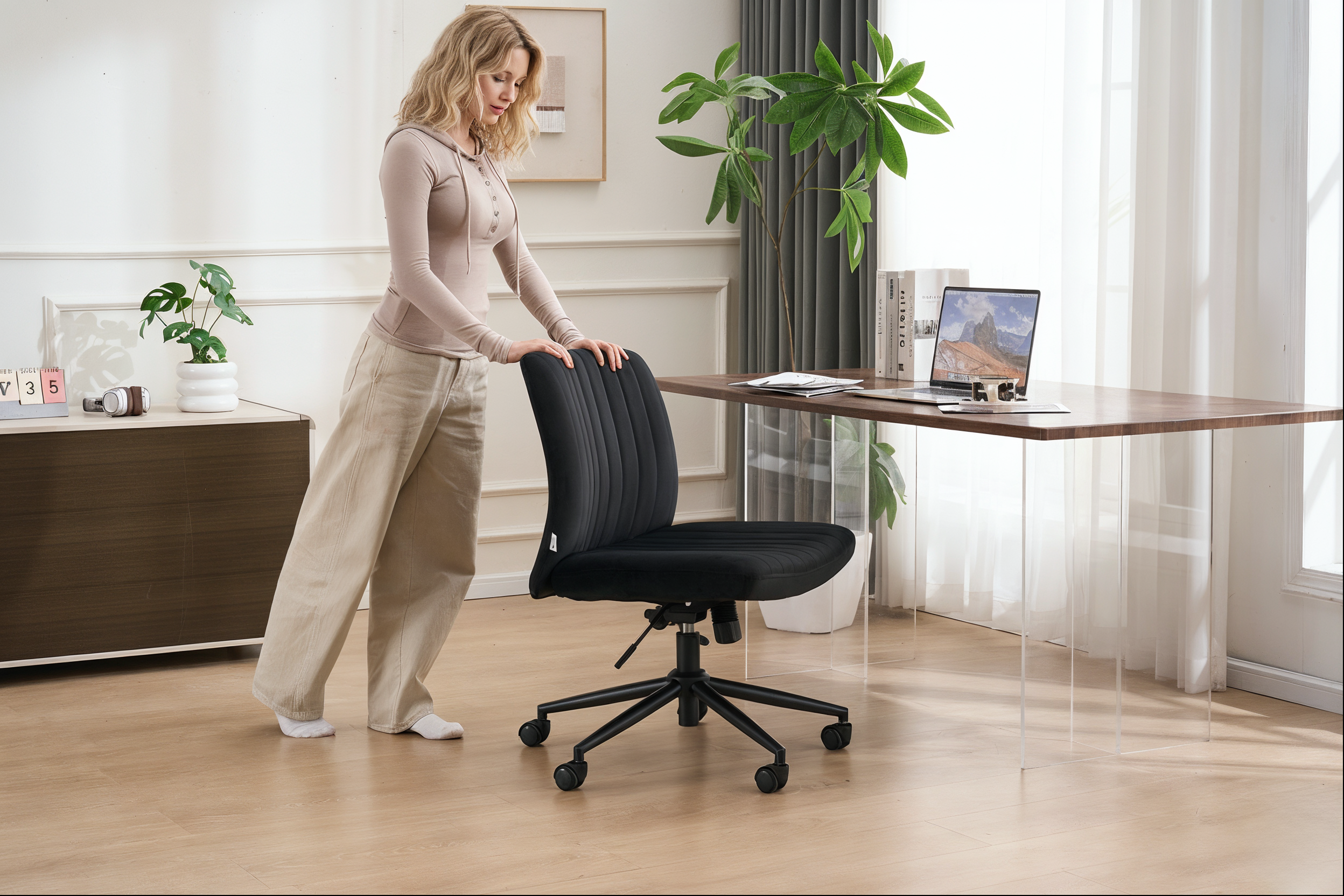 Woman adjusting height of sit-stand desk with ergonomic chair in bright home office workspace